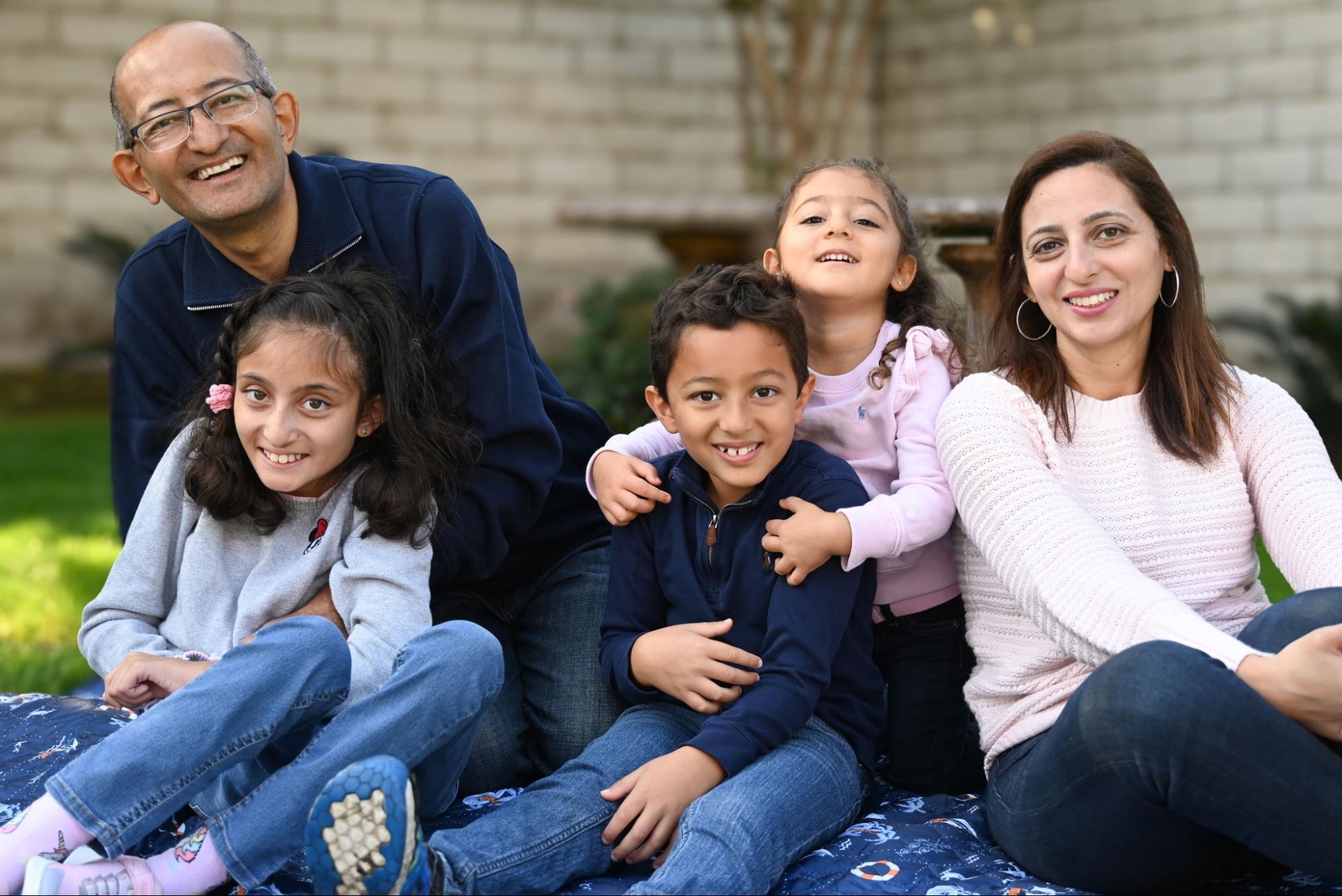 The family on a picnic blanket outside, all looking very happy.